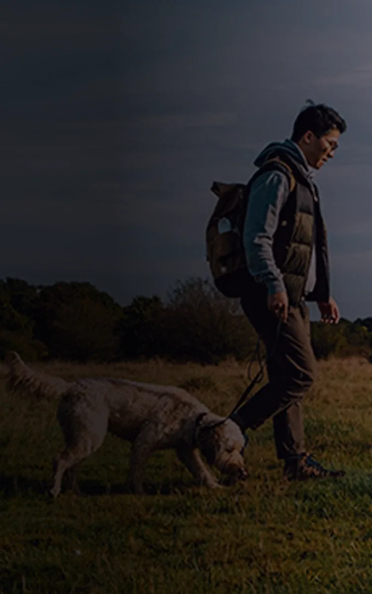 A man walking across a field with his dog