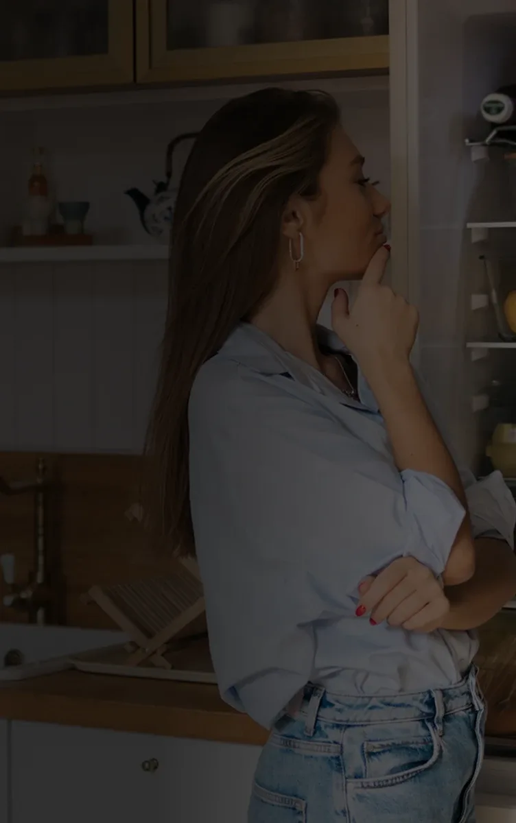 A woman looking into an open refrigerator in her kitchen