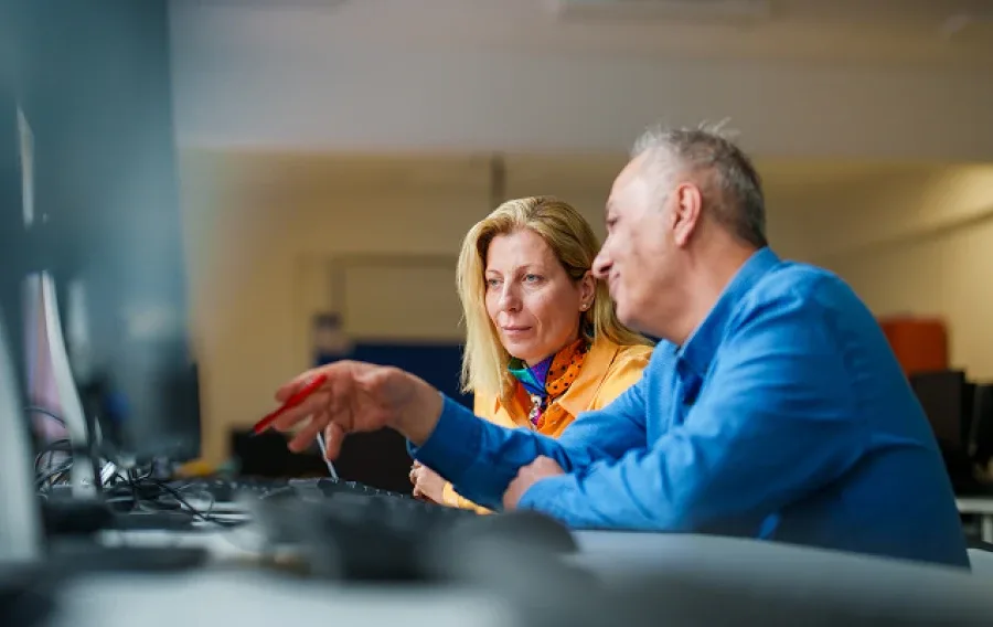 A man and woman looking at a computer screen together