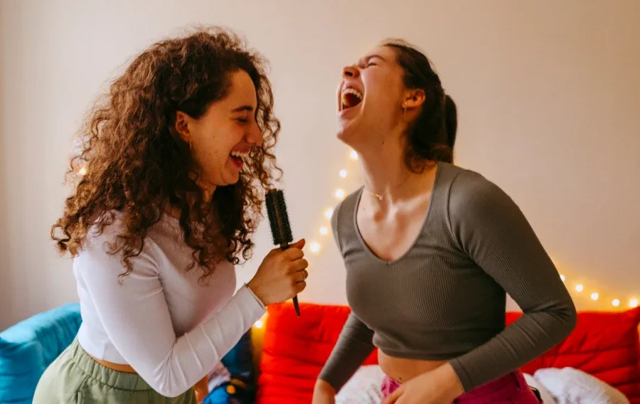 Two women singing into a hairbrush