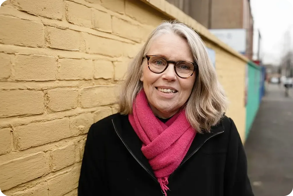 Jill smiling by a brick wall